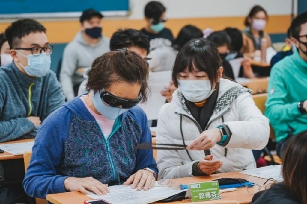 跑者戴上各式不同的眼鏡模擬視障者進行閱讀與書寫，實際感受視障者在生活上的種種不便利